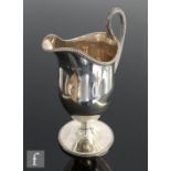 A Georgian hallmarked silver helmet cream jug of plain form with beaded borders and reeded handle,