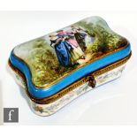 An early 20th century French painted porcelain casket of cushion form, the cover painted with a lady