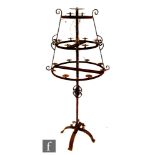 A cast iron floorstanding three tiered candle stand supported on a central column and scroll base,