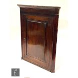 A George III mahogany hanging corner cupboard, the fixed shelf interior enclosed by a paneled door