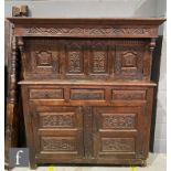 An 18th century and later carved oak court cupboard, the arched paneled back below a frieze