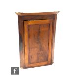 A 19th century mahogany hanging corner cupboard enclosed by a panel door and fixed shelf interior,