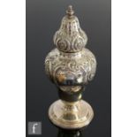 A hallmarked silver sugar castor of baluster form with part embossed foliate decoration, height