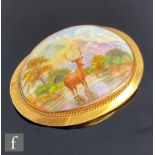 An early 20th Century 9ct mounted oval brooch, hand painted study of a standing stag in a