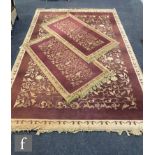 A modern Eastern rug, all over floral design on a maroon ground, 280cm x 97cm and a pair of matching