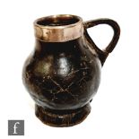A small late 17th to early 18th Century Blackjack jug of pot bellied form, with silver collar