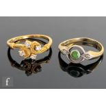 Two 18ct rings, a four stone diamond example with scroll shoulders and a three stone emerald and
