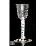 An 18th Century drinking glass circa 1760, the fluted round funnel bowl above single series opaque