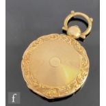 An early 20th Century circular locket with engine turned decoration within foliate border, weight