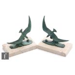 A pair of 1930s patinated green spelter figures of seagulls in flight above crashing waves,