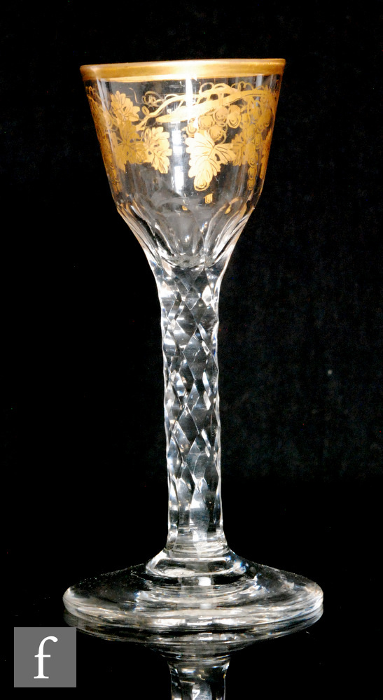 An 18th Century drinking glass circa 1770, the ogee bowl with basal flutes decorated with gilt rim