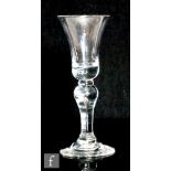 An 18th Century drinking glass circa 1730, the waisted bell bowl above teared inverted baluster stem