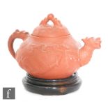 A Chinese Yixing red stoneware teapot of rounded squat form surmounted by a domed lid, relief
