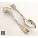 A pair of hallmarked silver fiddle pattern serving spoons each with engraved crest to terminal,