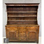 An 18th century oak dresser, the three tier rack below a fluted cornice over four central drawers
