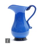 A blue glass jug circa 1800, of footed baluster form with applied scroll handle, all in a