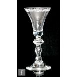 An 18th Century drinking glass circa 1745, the bell bowl engraved with a baroque scroll to the upper