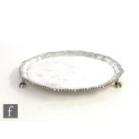 A hallmarked silver circular salver of plain form with gadroon scalloped border and raised on