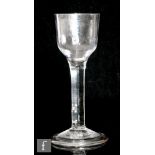An 18th Century drinking glass circa 1740, the basal fluted ogee bowl above a plain stem, raised