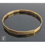 A 9ct hallmarked stiff bangle with alternating plain and Greek key engraved panels, weight 20g,