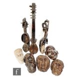 A group of five decorative Congolese carved hardwood wall masks and three Nepalese wooden stringed