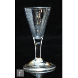An 18th Century dram glass circa 1750, the conical bowl above a plain stem and raised to a domed and