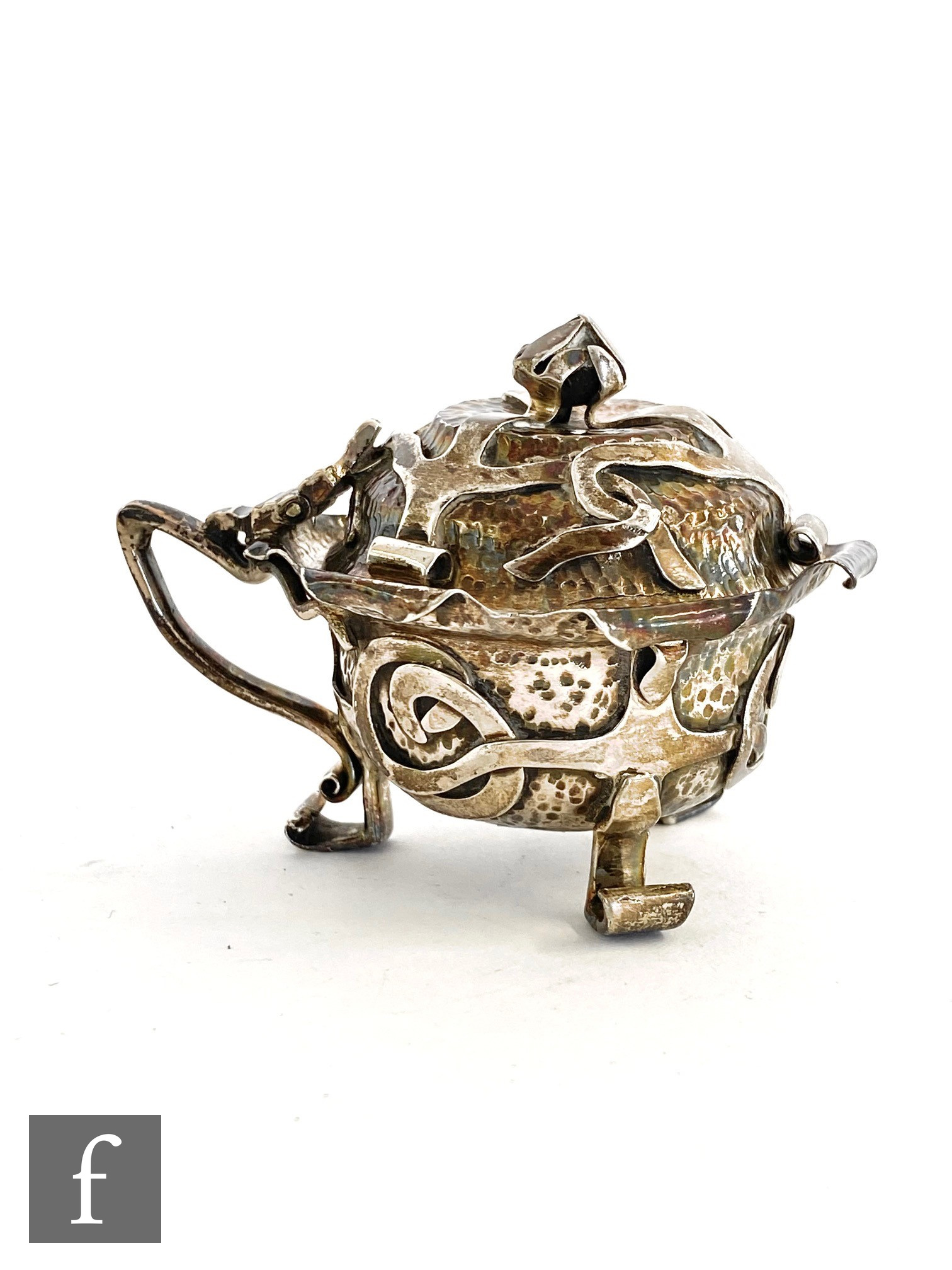 A hallmarked silver Arts & Crafts mustard pot with plain strap work over a beaten ground and