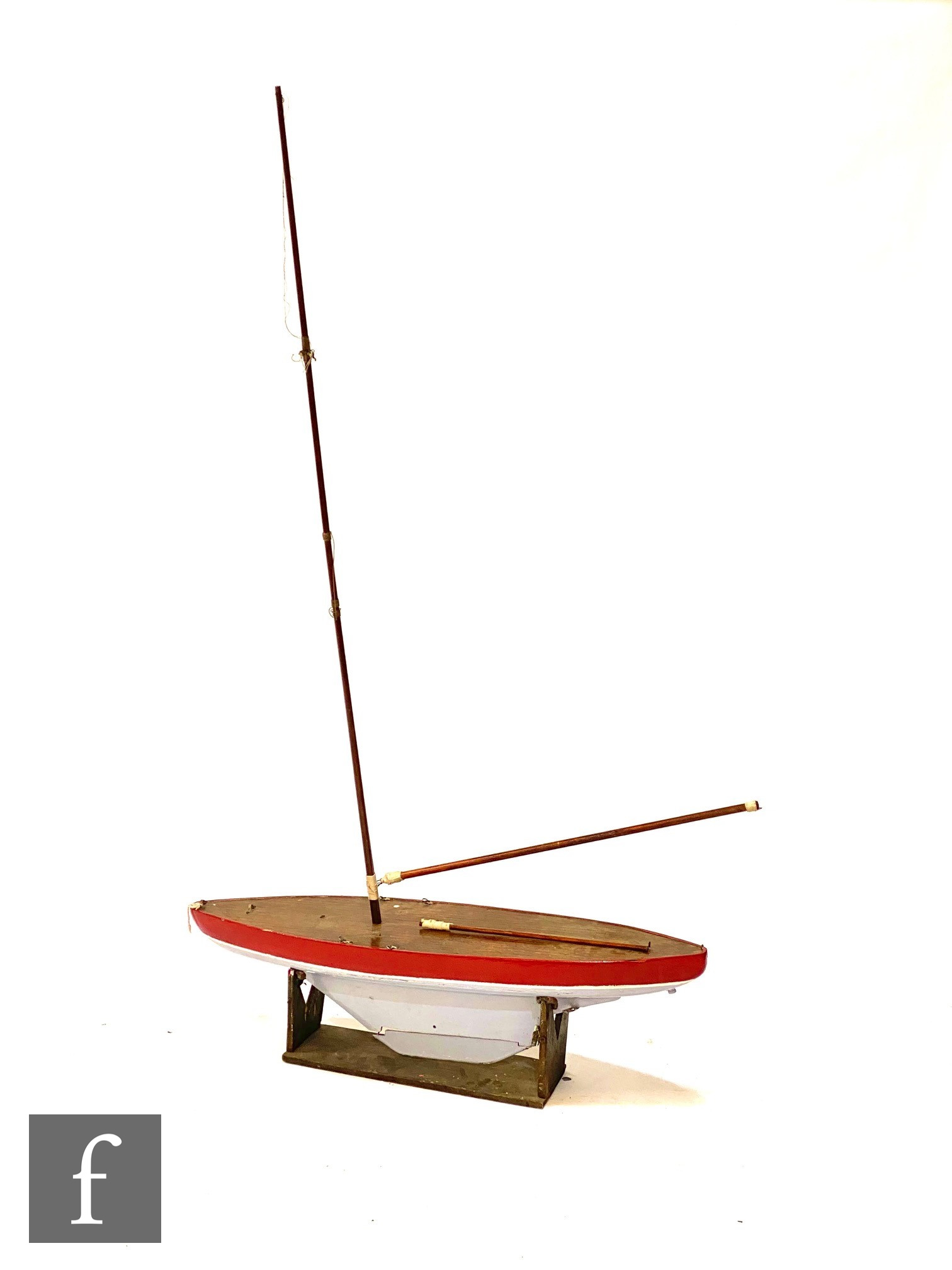 A mid 20th Century wooden pond yacht painted red and pale blue, single wooden mast, on associated