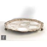 A hallmarked silver circular salver of plain form raised on three scroll feet and terminating in