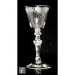 An 18th Century drinking glass circa 1765, the round funnel bowl engraved with a band of flowers and