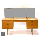 A 1970s teak dressing table, with a triple mirror above an arrangement of seven drawers, raised to