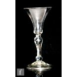 An 18th Century drinking glass circa 1730, the bell shaped bowl above a baluster steam with internal