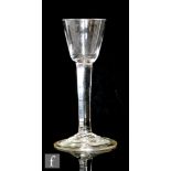 An 18th Century drinking glass circa 1750, the round funnel bowl above a solid plain stem, raised to