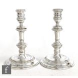 A pair of hallmarked silver piano candlesticks with circular stepped bases, knopped columns and