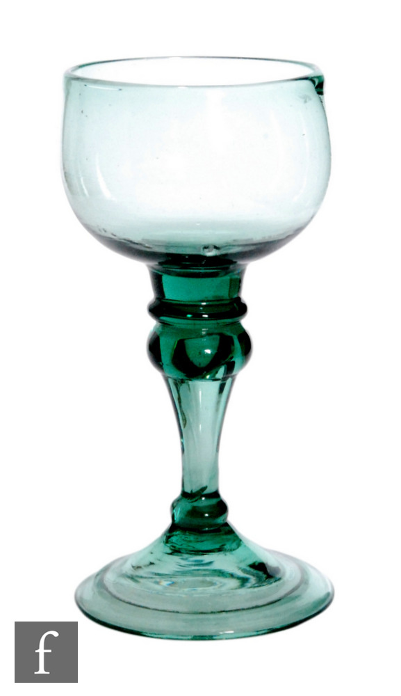 An 18th Century pale green drinking glass, circa 1750, the compressed cup bowl above shoulder