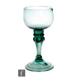 An 18th Century pale green drinking glass, circa 1750, the compressed cup bowl above shoulder