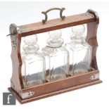 An oak cased three bottle tantalus with plated mounts and carry handle, each decanter of square form