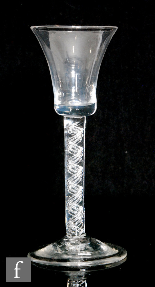 An 18th Century drinking glass circa 1750, the flared bucket bowl above air twist stem with four