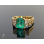 An 18ct emerald and diamond ring, central claw set emerald cut emerald, length 8mm, flanked by two