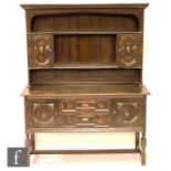 A 1920s oak dresser centred by two geometric moulded front drawers flanked by cupboards below a