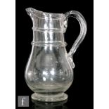 An early 19th Century glass cider jug of baluster form, with foldover rim, two applied bladed