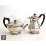 A hallmarked silver teapot and hot water jug each with gardroon circular foot below plain bodies,