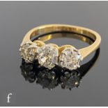 An 18ct diamond three stone ring, old cut claw set stones to knife edged shoulders, total diamond