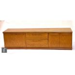 A 1970s teak sideboard, fitted with an arrangement of a double door cupboard to each side of the