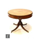 A George III style circular mahogany drum table, the frieze fitted with drawers, on turned fluted