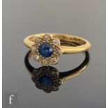 An early 20th Century sapphire and diamond daisy cluster ring, central sapphire within a border of