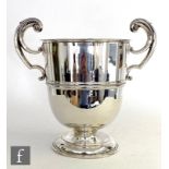A hallmarked silver twin handled pedestal cup of plain form, circular stepped foot rising to leaf