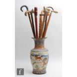 A collection of twelve walking sticks to include horn, brass and rootwood examples, all in a