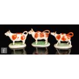 Three 19th Century Staffordshire cow creamers and covers each with brown sponged patches and