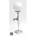 An Art Deco chrome table lamp of a nude silhouette figure holding a white globe, height 52cm.